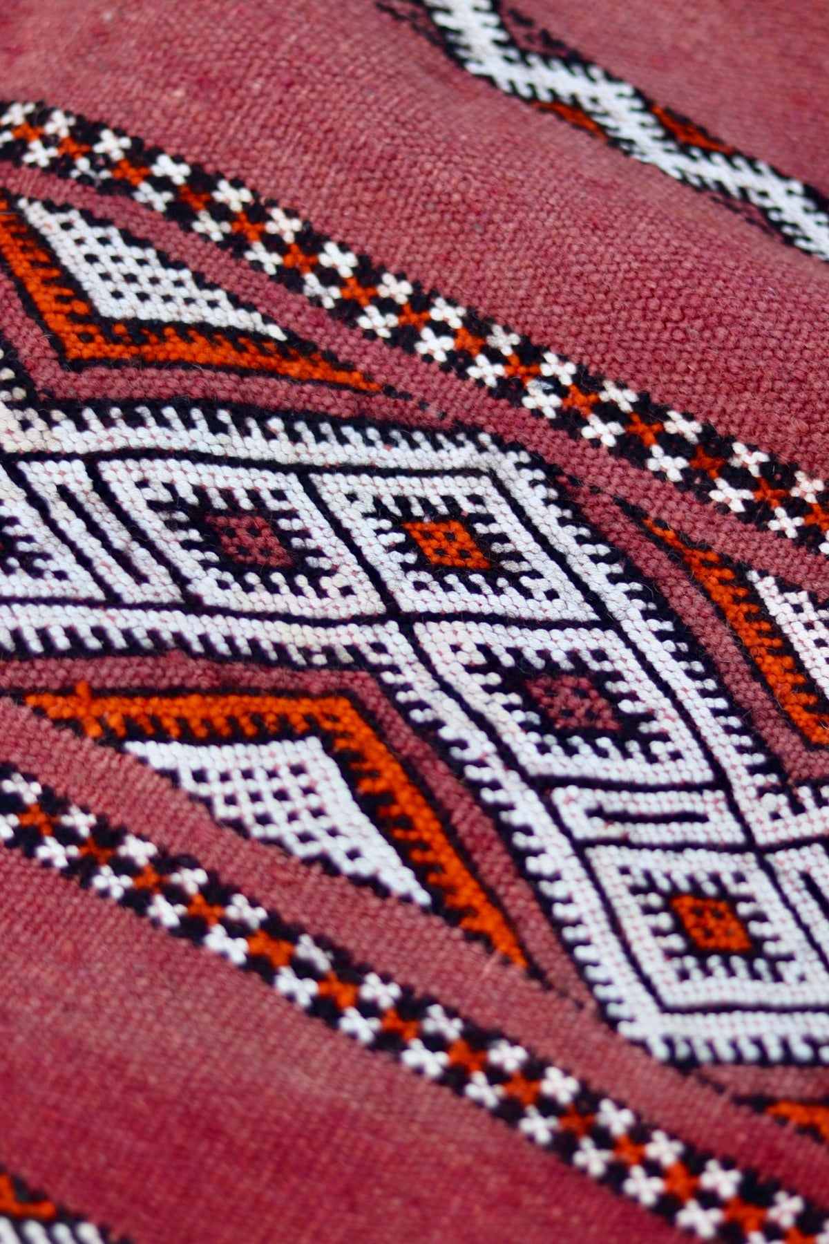 Close-up of the textured red weave and cream, black and orange diamond pattern