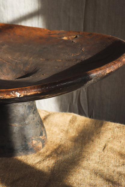 Rust-colored metal bowl on a textured surface with a neutral background