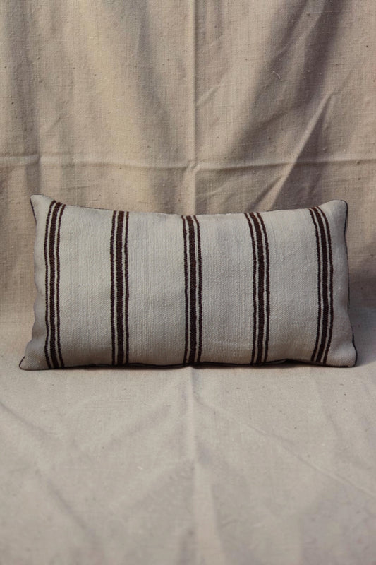 Long cream Moroccan cushion cover with five bands of dark brown triple stripes on a linen backdrop