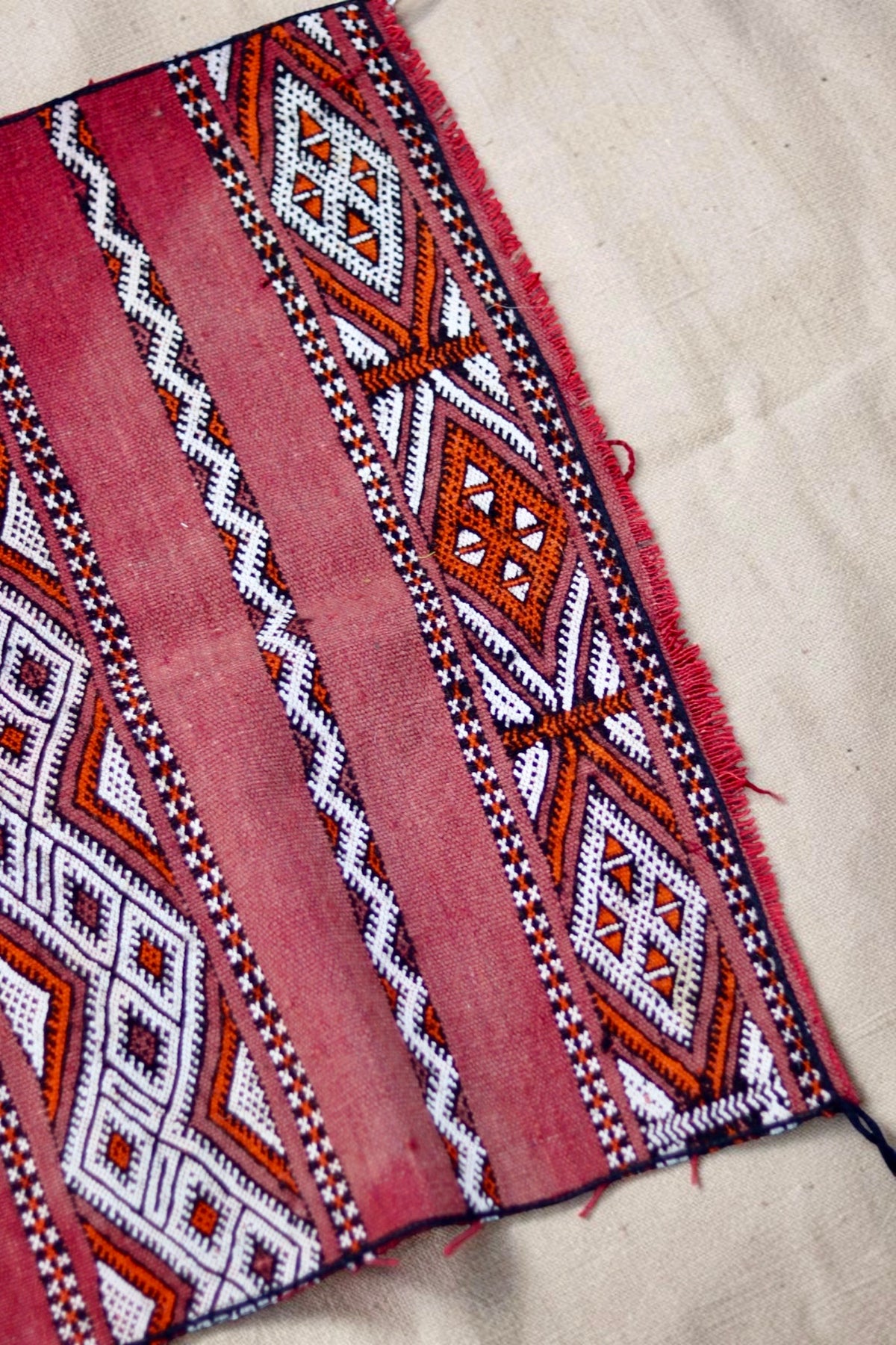Edge and fringe detail with cream and orange diamond motifs