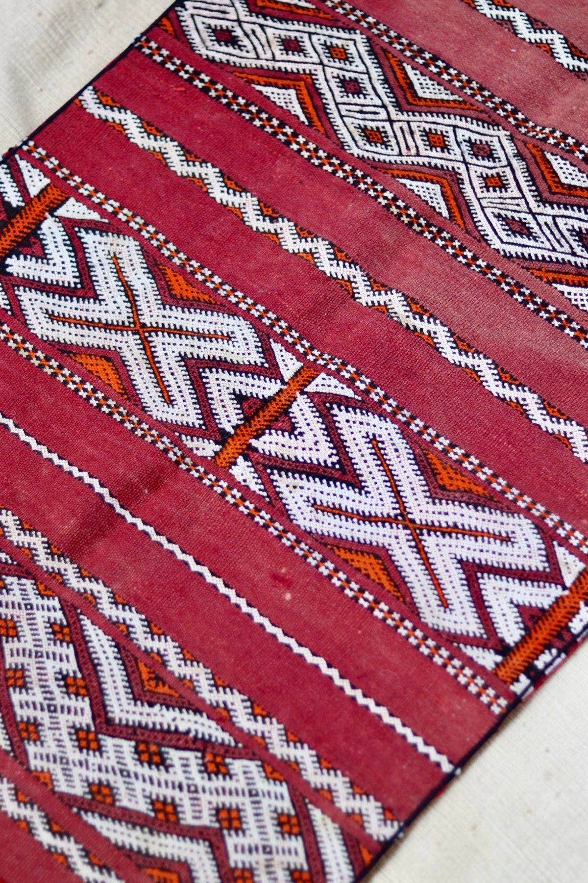 Cream and black geometric bands with orange accents on the faded red Hanbel rug