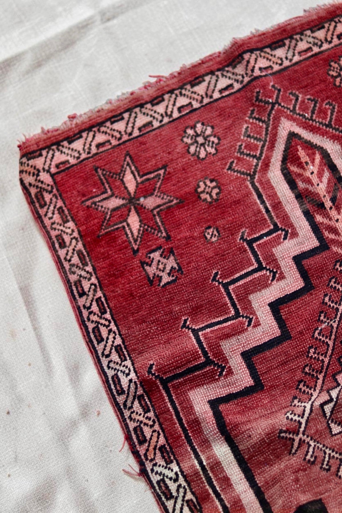 Corner detail with a pink star motif, dark outlines and worn edging