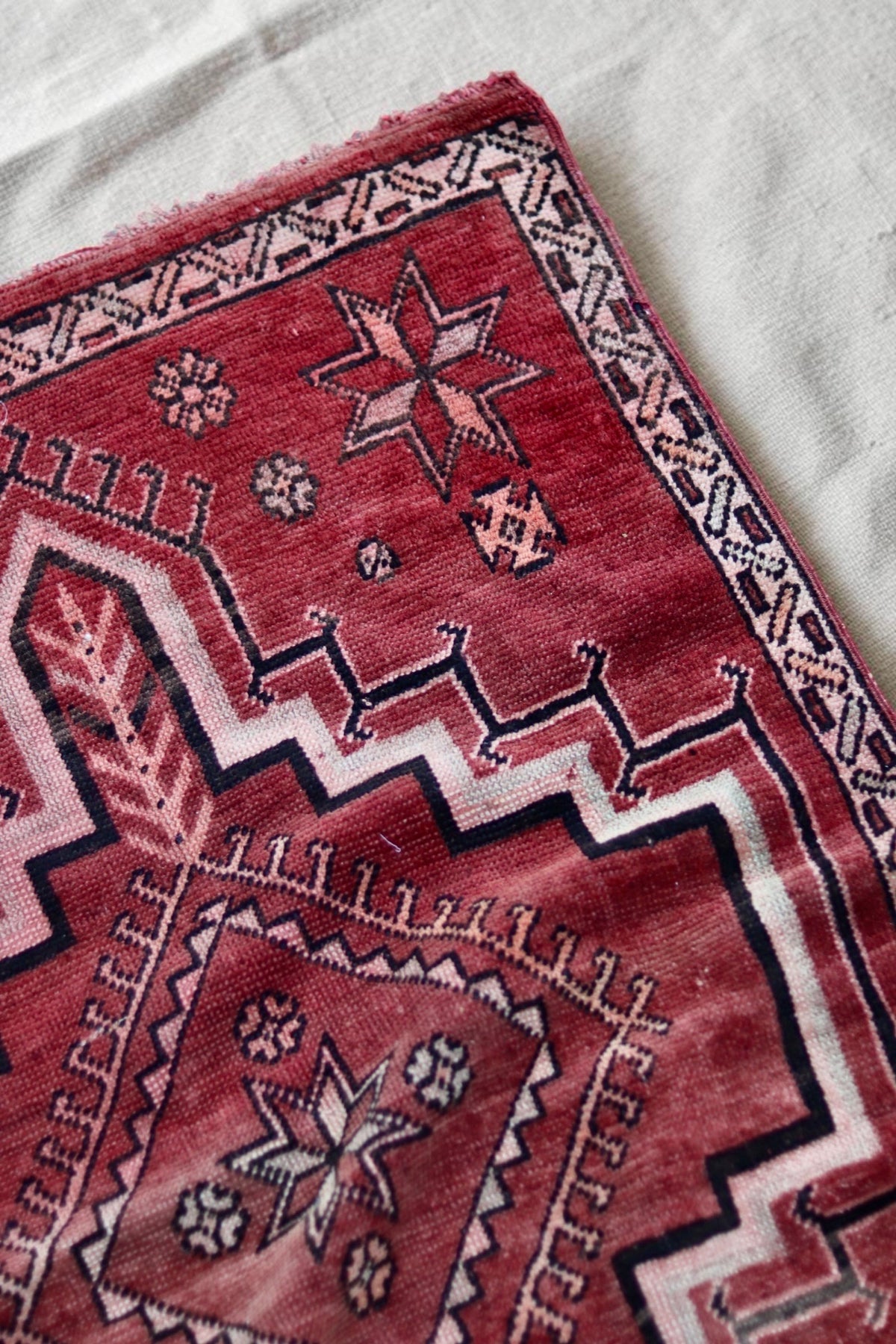 Star motif, patterned pink border and colour variation in the red vintage rug