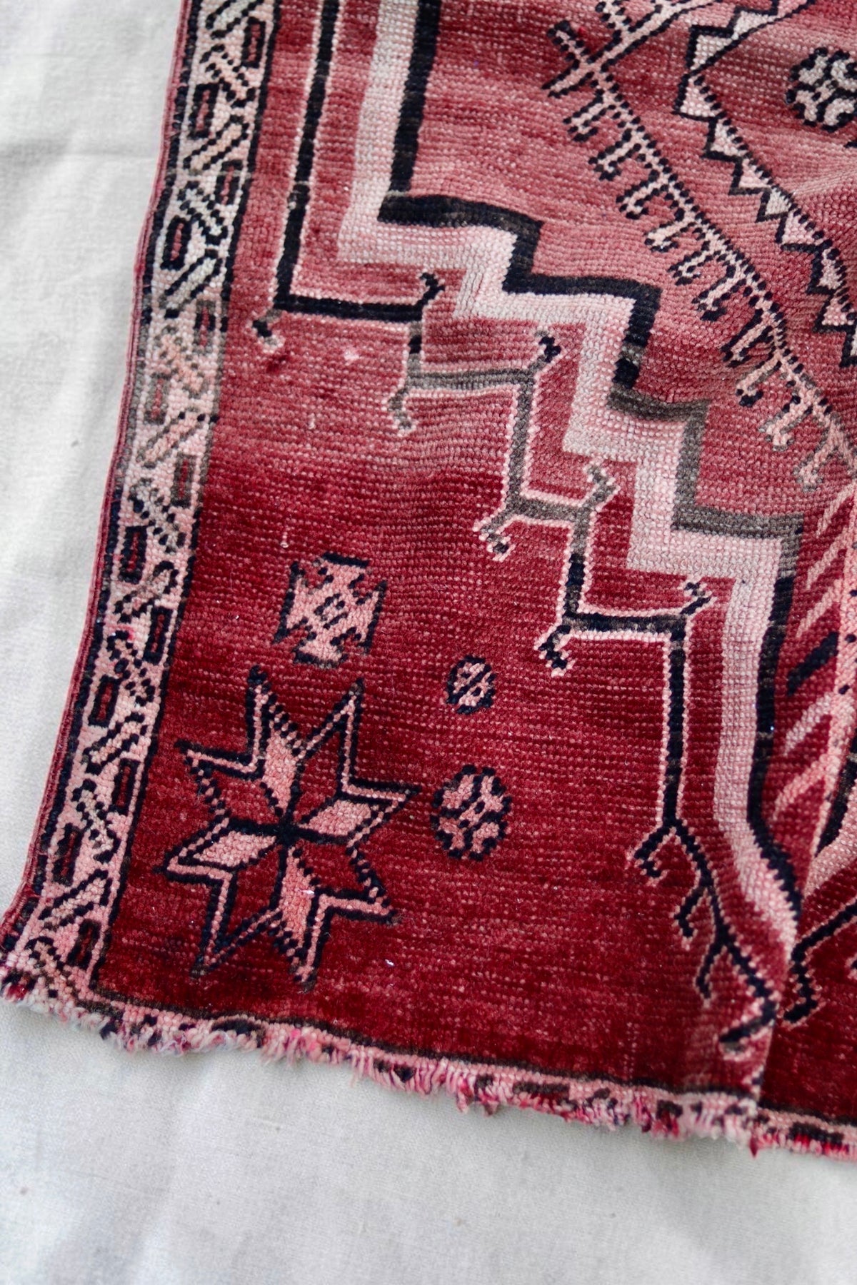 Close-up showing uneven fading, worn areas and fraying at the end of the vintage rug
