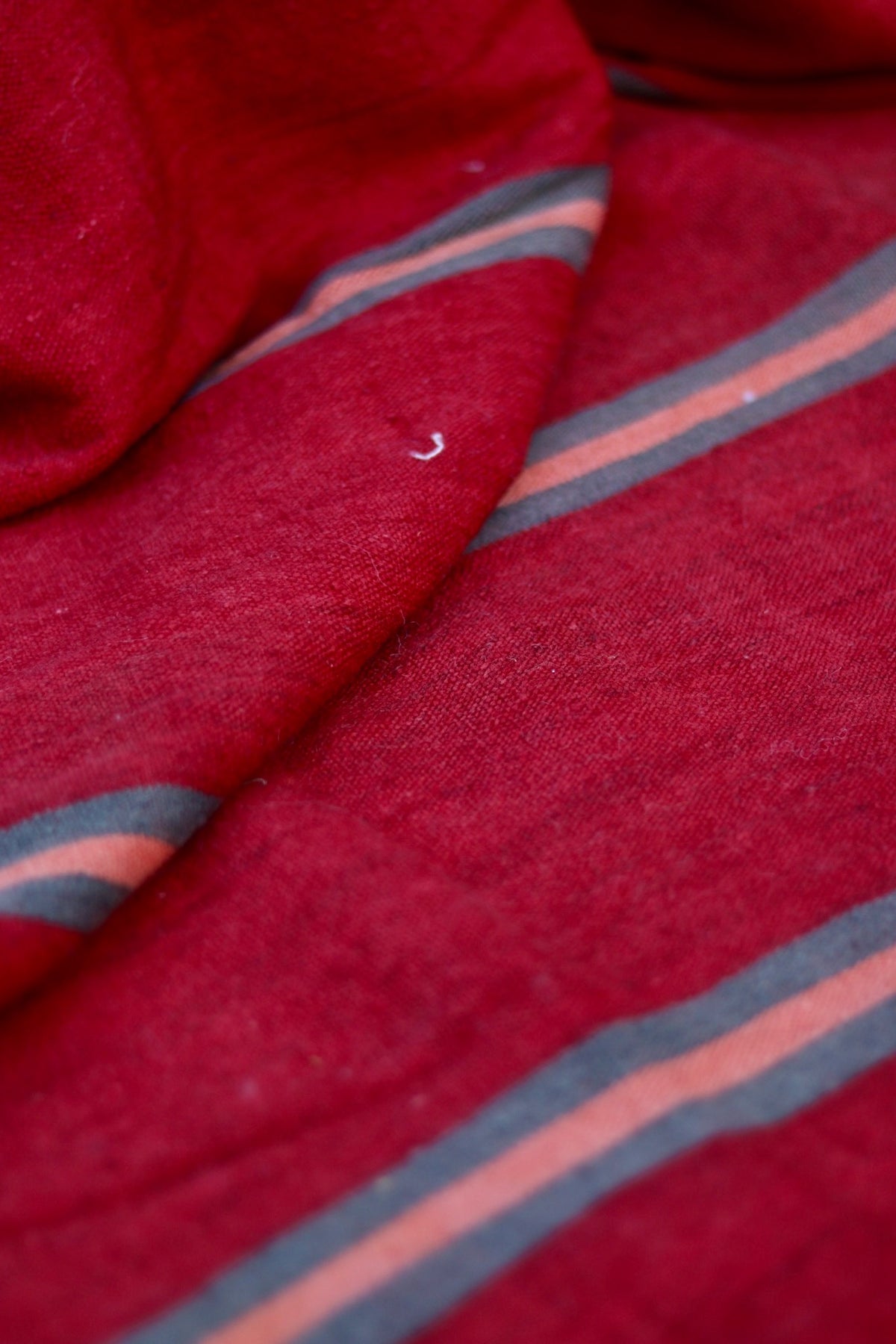 Draped red flatweave showing its thin pliable weave and narrow stripes