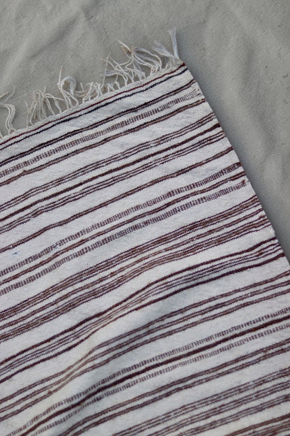 Corner and fringe detail showing fine brown stripes in the cream weave