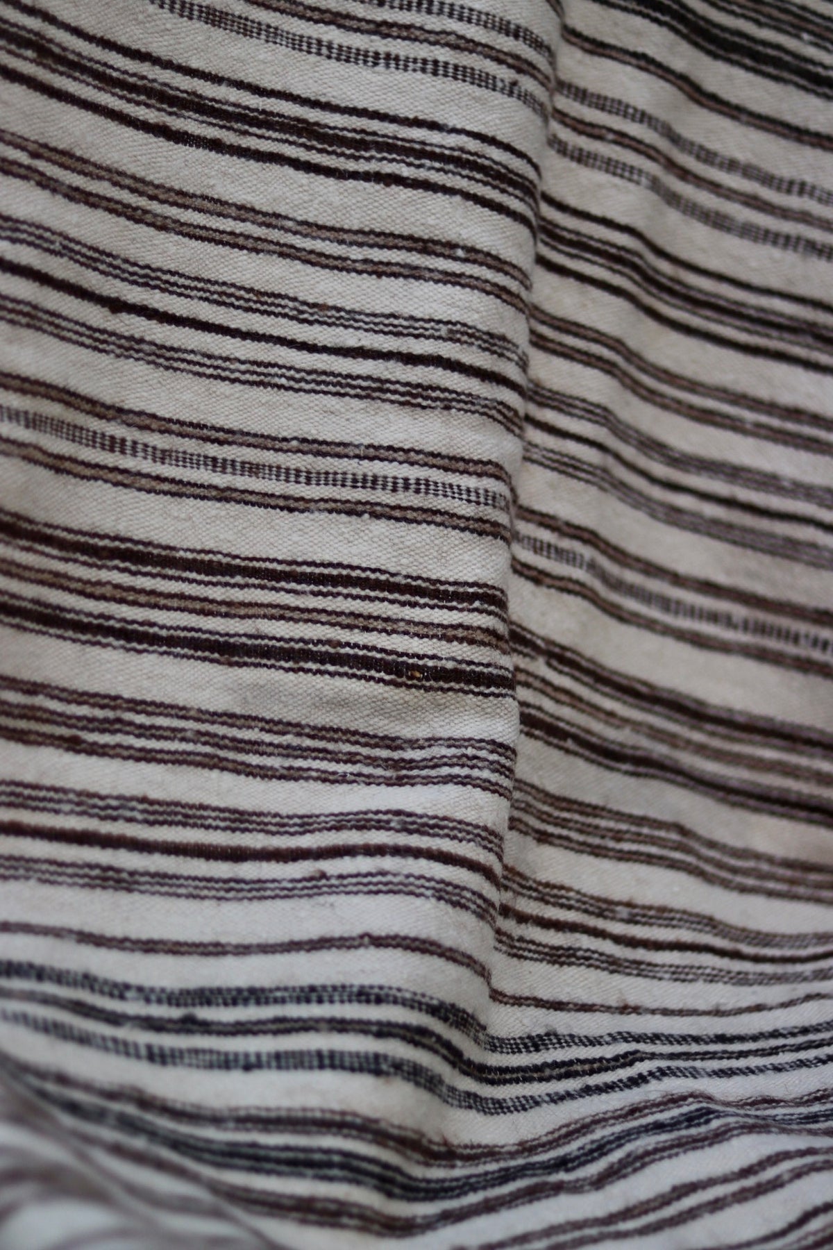 Close-up of irregular brown and charcoal stripes woven into the cream ground