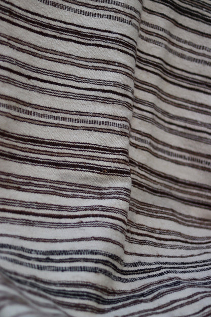 Close-up of irregular brown and charcoal stripes woven into the cream ground