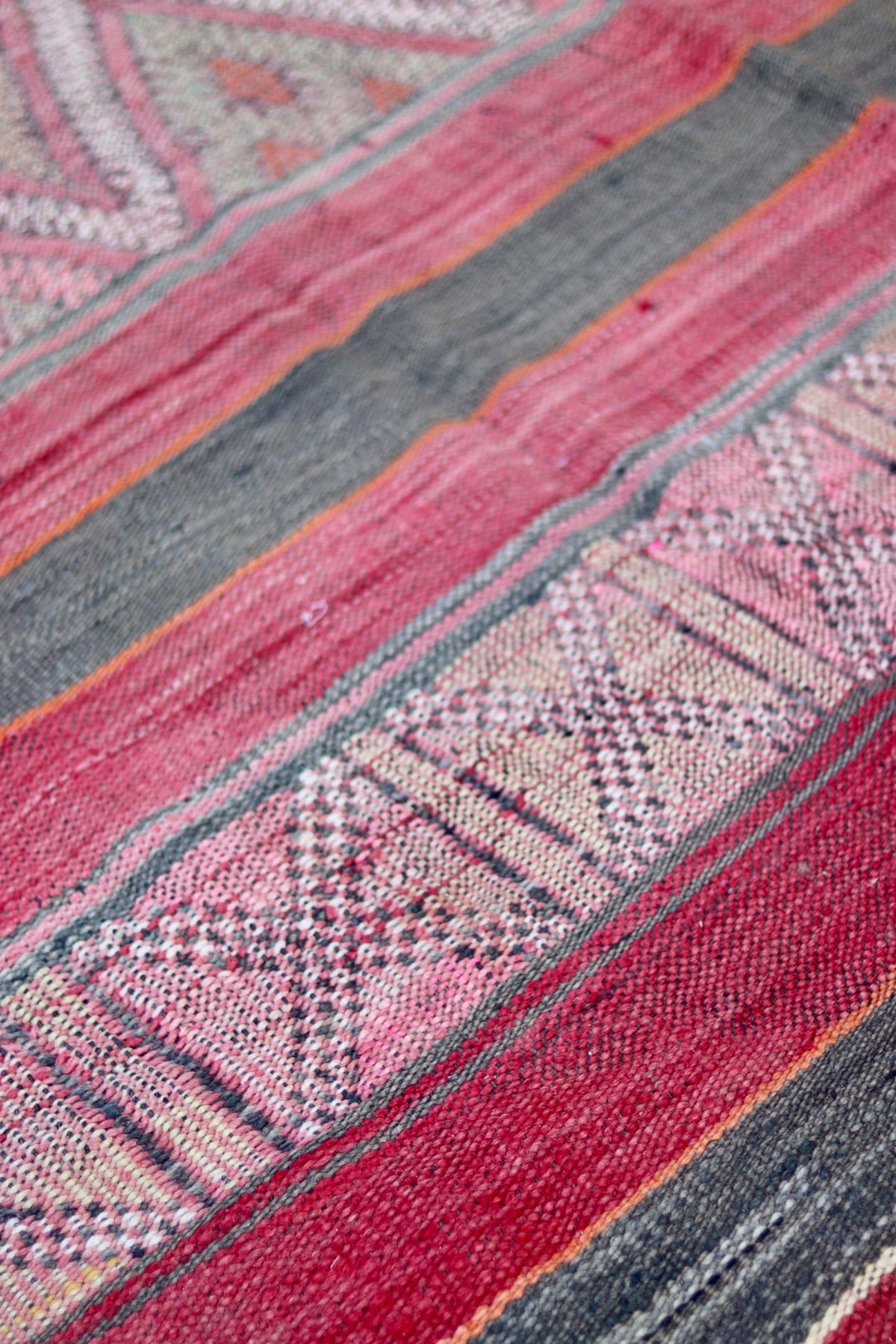 Woven diamond motifs between faded red and charcoal stripes