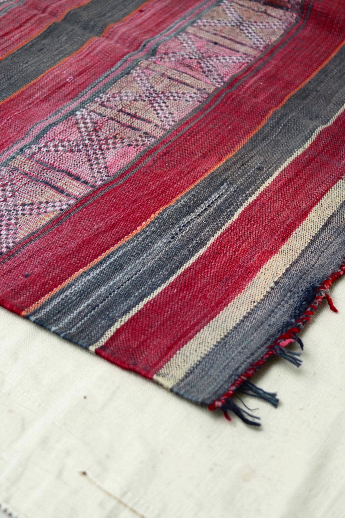 Faded geometric bands and striped end of the vintage Hanbel rug
