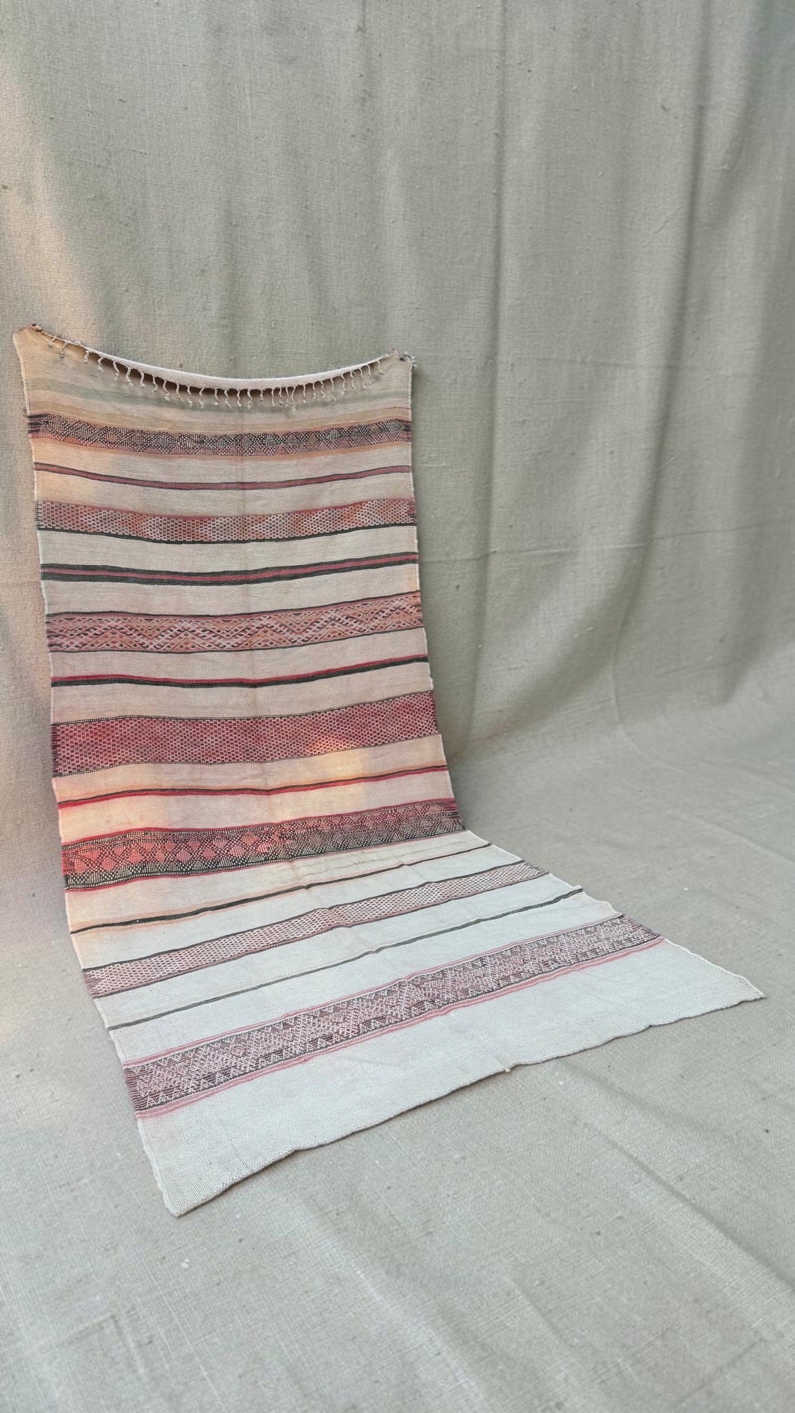 Angled view of the large cream and rose vintage Moroccan Hanbel rug