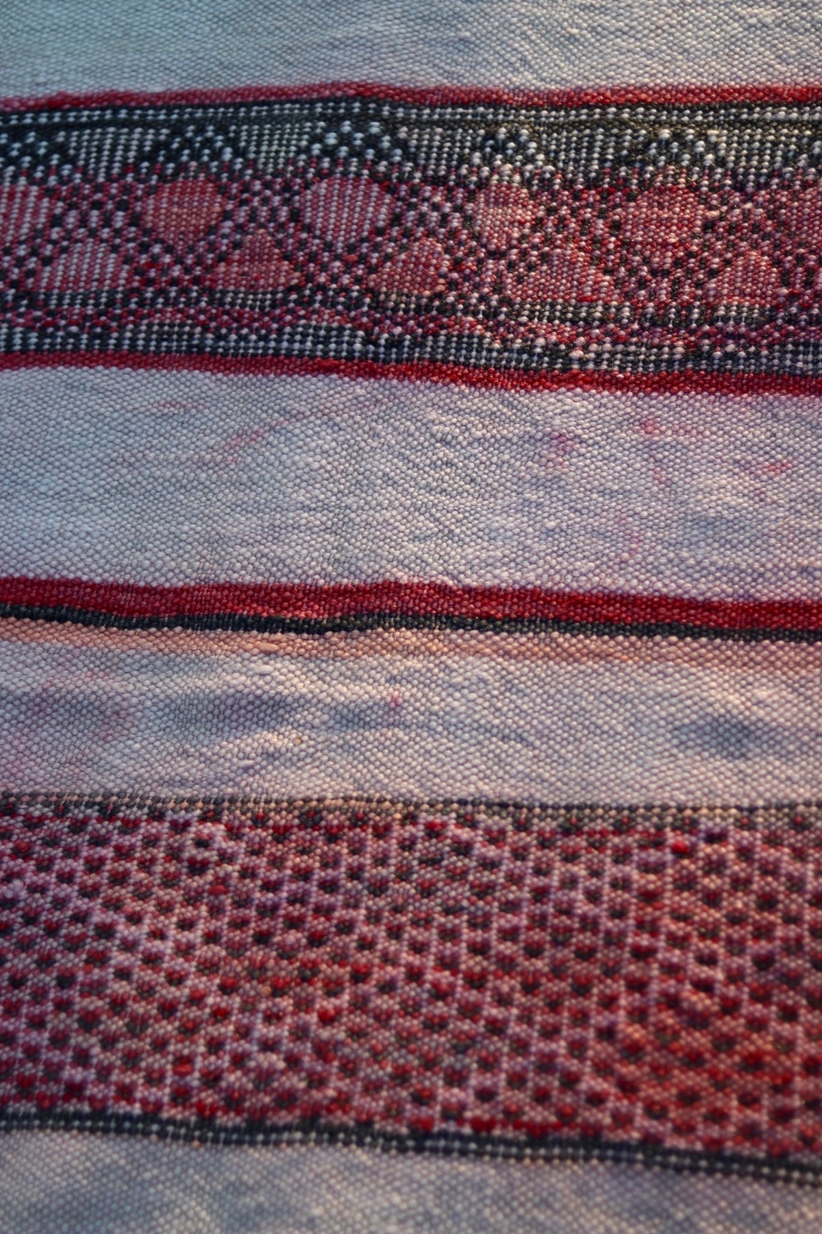 Close-up of rose and charcoal diamond motifs across the cream Hanbel rug