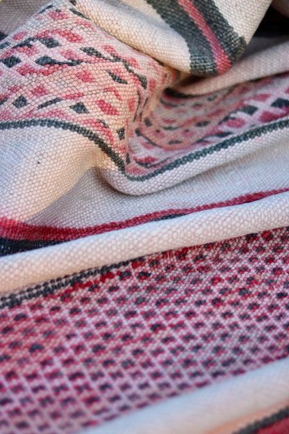 Draped detail of the cream and rose rug showing diamond and narrow stripe patterns