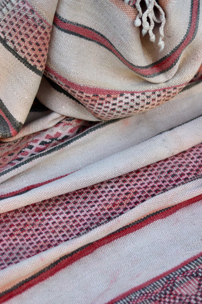 Folded vintage Hanbel rug showing its weave, geometric bands and knotted fringe