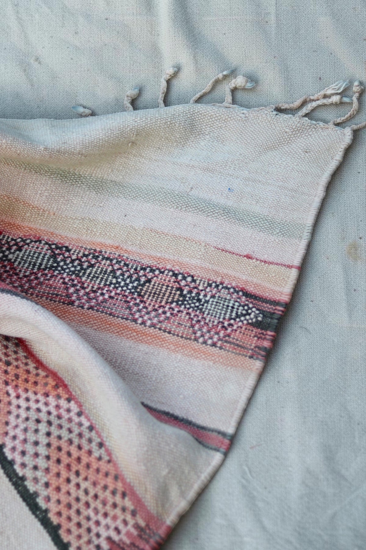 Folded corner showing the cream flatweave and pink and charcoal diamond pattern