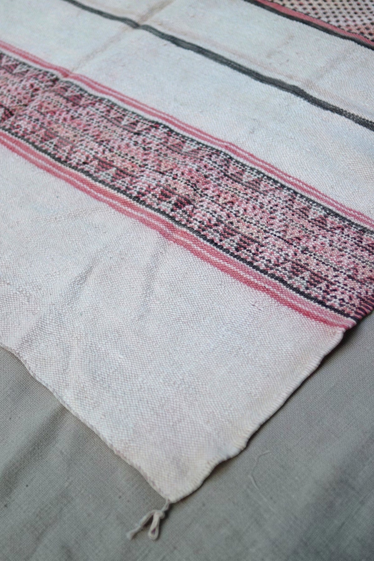 Plain end of the Hanbel rug with a rose and charcoal geometric band