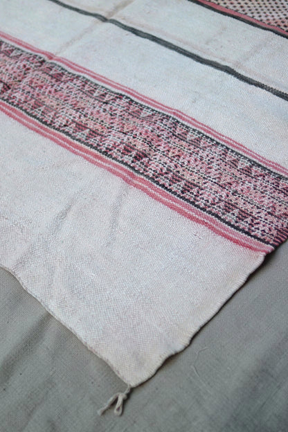 Plain end of the Hanbel rug with a rose and charcoal geometric band