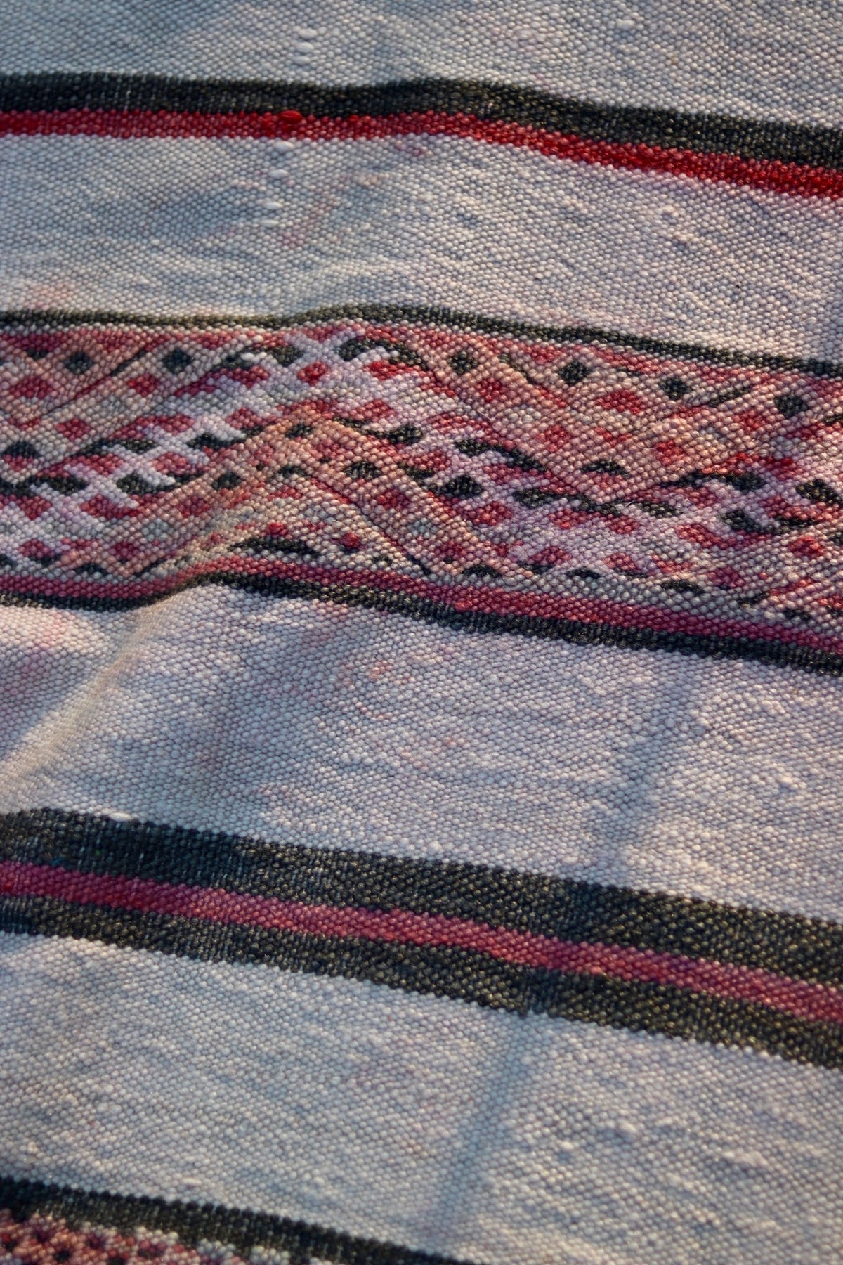 Detail of the stepped geometric band and uneven texture of the cream flatweave