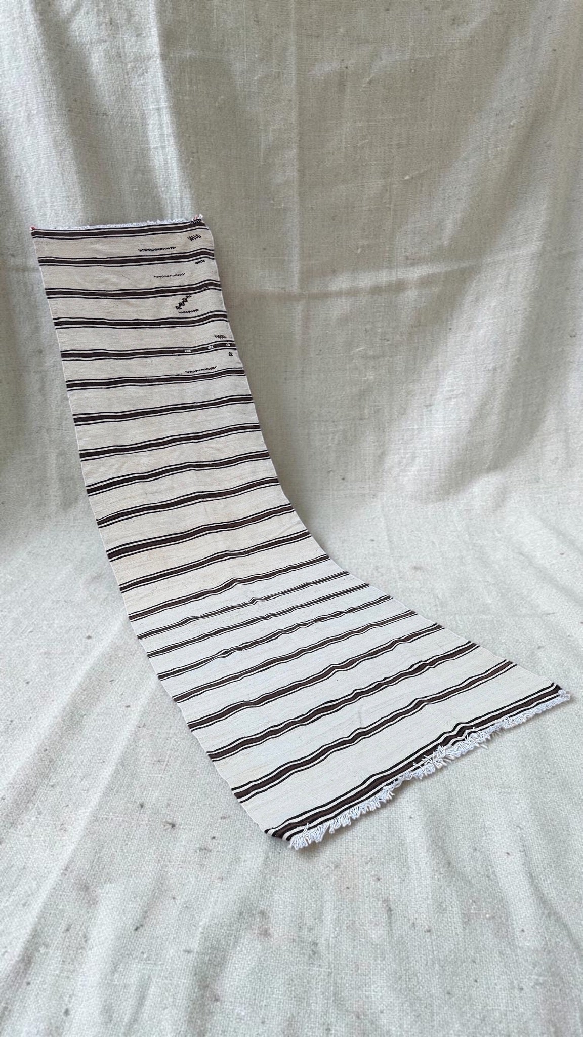 Angled full view of the extra-long cream and brown striped flatweave runner
