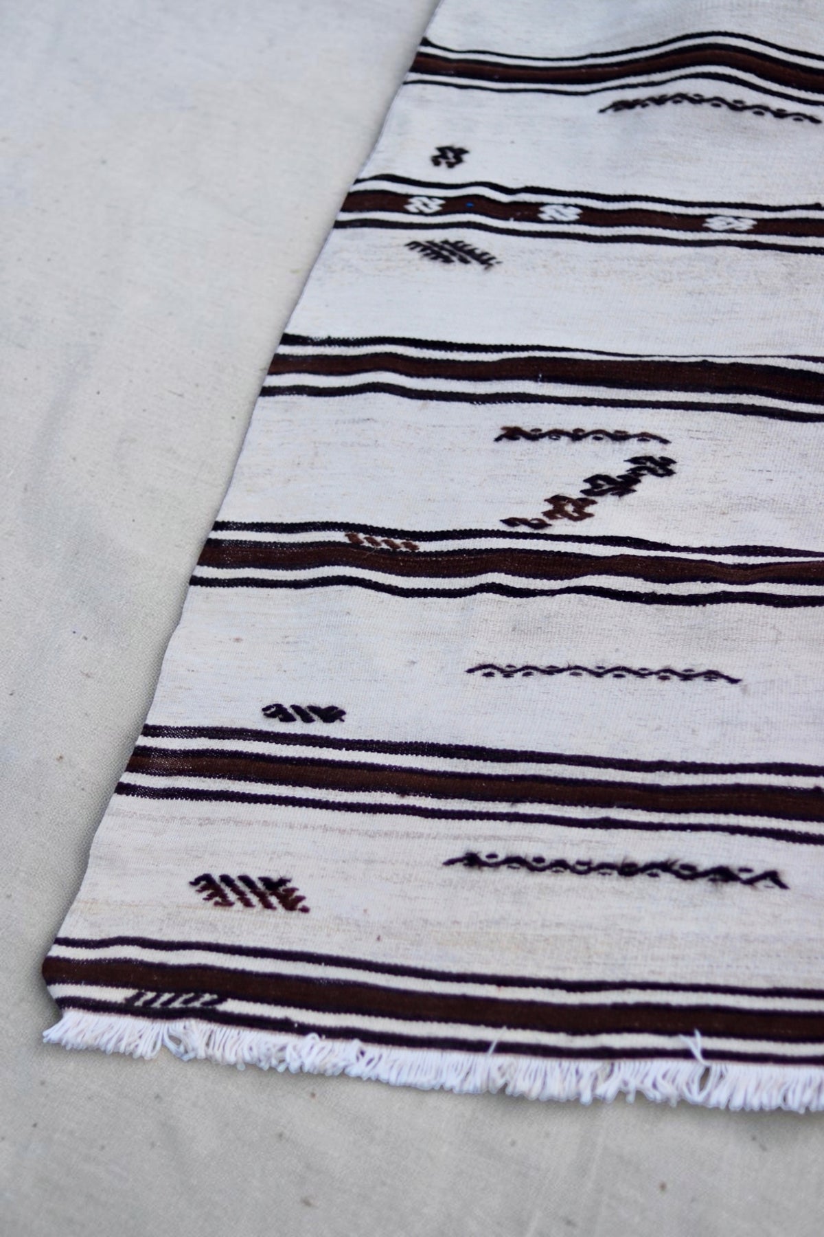 Detail of the scattered geometric motifs, brown stripes and pale fringe
