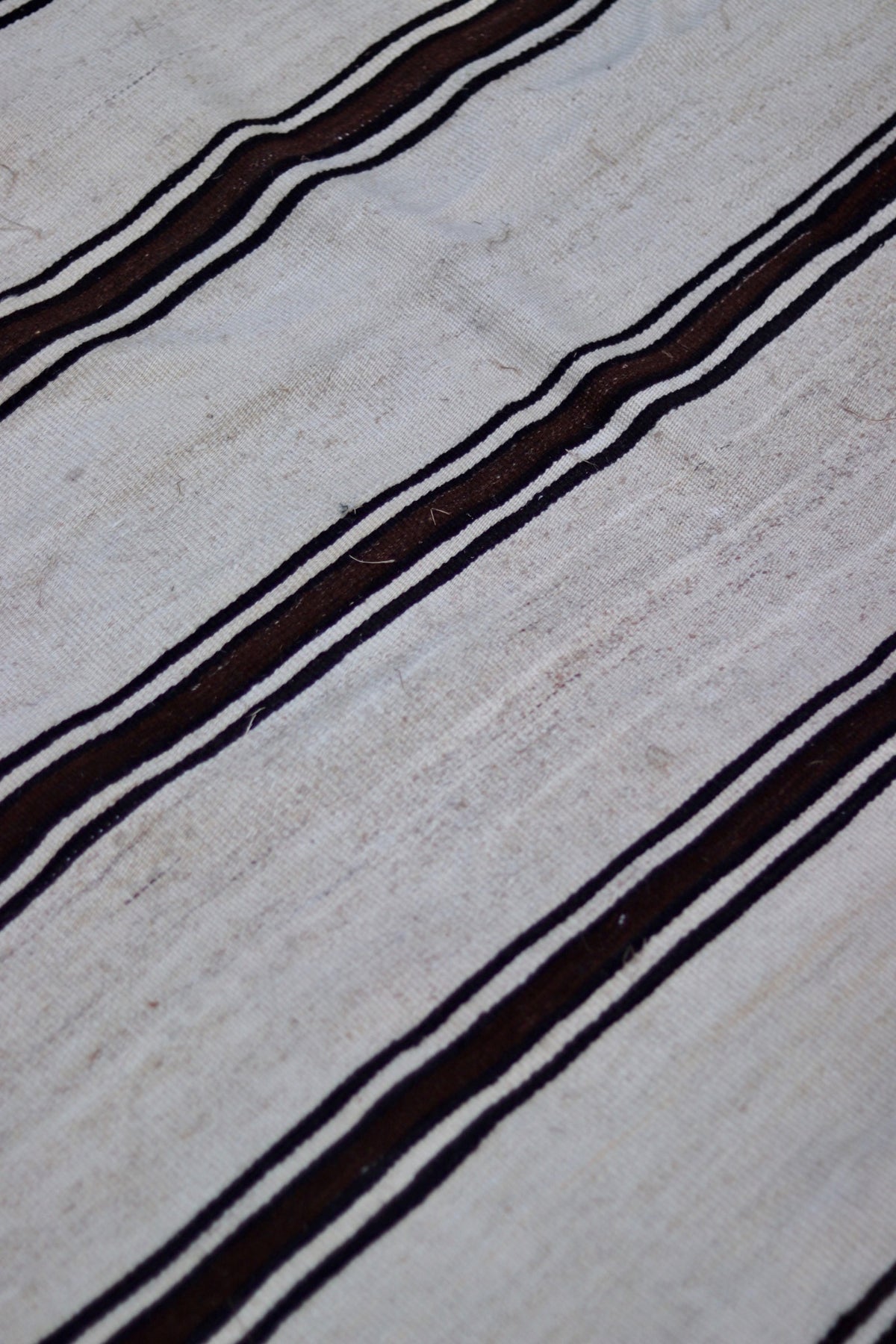 Close-up showing the weave, small marks and tonal variation in the cream ground